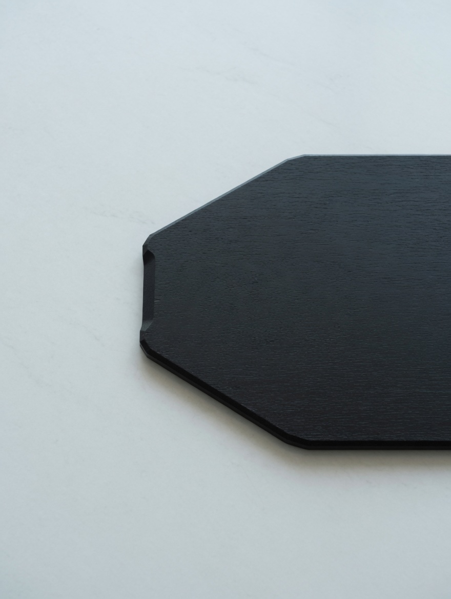 An octagonal blackened oak platter, edge detail